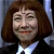 Pixelated static image of a person with shoulder-length brown hair wearing dark clothing and white shirt collar, smiling with closed eyes against blurred background.