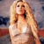 Pixelated image of a person with long blonde hair wearing a light-colored top, standing against a blurred background with indistinct shapes and colors.