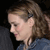 Pixelated side profile of a person with light brown hair tied back, wearing a blue garment against a dark background.