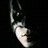 A pixelated, low-resolution image of a stylized bat symbol with curved wings and a pointed tip against a dark background.