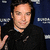 Pixelated image of a person with dark hair wearing black clothing against a blue background with white horizontal lines.
