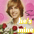 A pixelated image of a person with brown hair holding red roses against a pink background, featuring overlaid text in yellow, green, and red.