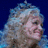Pixelated image of a person with curly light-colored hair against a dark blue background, with pink text reading "it's only a pair of shoes let it go" in a