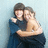 Two figures embrace in a pixelated static image; one wears dark clothing, the other light-colored attire, against a pale blue background.