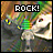 Pixelated image with 'ROCK!' text above a stylized figure holding a green object against a multicolored background.