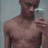 A shirtless man with dark skin stands against a gray background, while sand forms the shape of a heart on a beach.