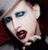 Static pixelated image of a stylized face with exaggerated features and dark background, likely representing a musician or public figure in low-resolution digital art style.