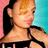 Pixelated close-up of a person with light brown hair tied back, wearing a black top against pink and cyan background.