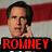 A pixelated image of a man with dark hair and glasses, wearing a suit, holding his hand near his face against an American flag background.