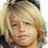 Static pixelated image of a person with light brown hair and closed eyes, wearing dark clothing against a blurred background.