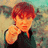 A person with reddish-brown hair points directly at the viewer against a blurred background, with text appearing in one frame.