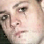 Pixelated close-up of a person's face showing eyes, nose, and mouth with visible skin tones and dark hair strands.