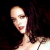Pixelated static image of a person's face and upper body with dark hair against black background, showing partial facial features and clothing details.
