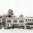 Pixelated grayscale image of a building facade with multiple rectangular windows and a rounded architectural feature on the left side.