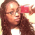A pixelated image of a person with long brown hair holding a red object near their face, next to large black and white stylized text.