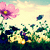 Pixelated image of a pink flower with purple center and yellow stamen, green leaves, and scattered blue and green shapes against a light background.