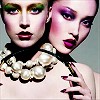 Two stylized female faces with dramatic makeup and a large pearl necklace, one holding a makeup brush.