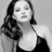 Black-and-white pixelated static image of a person with shoulder-length hair wearing a sleeveless top, displayed on a gray background.