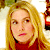 Static 50x50 pixel icon showing a close-up of a person with long blonde hair wearing a red top, partially visible background elements including green and brown tones.