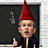 Static 48x48 pixel buddy icon featuring a cartoon character with a red pointed hat, light skin tone, and dark suit against a black background with faint greenish patterns.