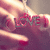 A hand with red-painted nails holds a small object with the word LOVE in gray letters, set against a blurred background.