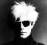 Pixelated grayscale icon of a human skull with hollow eye sockets and nasal cavity against dark background.