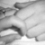 Black-and-white image of a hand holding multiple rounded objects with visible shadows and texture variations.