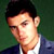 Static pixelated image of a person's face and upper torso in formal attire against a dark green background.