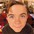 Static 50x50 pixel icon showing a person's face with brown hair and neutral expression against blurred background elements.