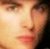 Pixelated close-up of a human face with warm skin tones, visible eyes and nose, and blurred background.