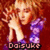 Pixelated image of a person with light brown hair holding a purple object against a red background, with text at the bottom.