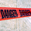 Red tape with black text reading "DANGER" repeated twice, displayed against a blurred background of light-colored fabric.