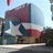 Pixelated image of a building with a maroon roof and blue structural elements under a light blue sky.