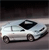 Static pixelated image of a white convertible car with black roof and wheels on a gray road under dark sky.