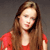 A pixelated portrait of a person with long brown hair wearing a red top against a gray background.