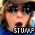 Pixelated close-up of a person with light brown hair and dark sunglasses, mouth open in an exaggerated expression, overlaid with bold black-and-white text reading STUMP.