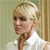 Pixelated image of a person with short blonde hair wearing a white collared shirt against a light green and beige background.