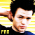 Pixelated image of a person with dark hair against yellow and white striped background, wearing black top with blue collar, text 'FAN' in yellow at bottom left.