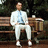 A pixelated image of a person in white clothing sitting on a bench next to a table with objects, alongside blue background text reading 'i ran a long way'.