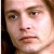 Pixelated close-up of a person's face with light skin tone, brown hair, and neutral expression against a blurred background.