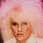 Pixelated close-up of a person with light skin and brown eyes against a pink floral background, wearing a white top.