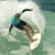 Pixelated static image of a person surfing on a white board in green water with light background.