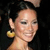 Pixelated close-up of a person with dark hair, light skin, and a yellow earring against a dark background.