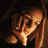 Pixelated static image of a stylized figure with long hair and flowing clothing in warm brown/orange tones against dark background, rendered at low resolution with visible dithering and pixelation.