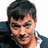 Static pixelated image of a person with short dark hair wearing a dark jacket over a light shirt, cropped to show the upper body against a white background.