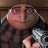 Pixelated character with large nose and wide eyes holding a small object, wearing dark clothing against wooden background.