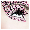 A close-up of a human eye adorned with pink and black gem-like decorations forming a pattern around the eyelid and upper cheek.