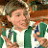 Pixelated image of a person with light skin wearing a white shirt and green jacket, holding a brown object near their face.
