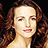 Pixelated close-up of a person with long brown hair against a black background, static image with no visible text or animation.