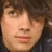 Pixelated portrait of a person with brown hair on left, cyan text 'joe jonas roxxxx!!!' on purple background right.